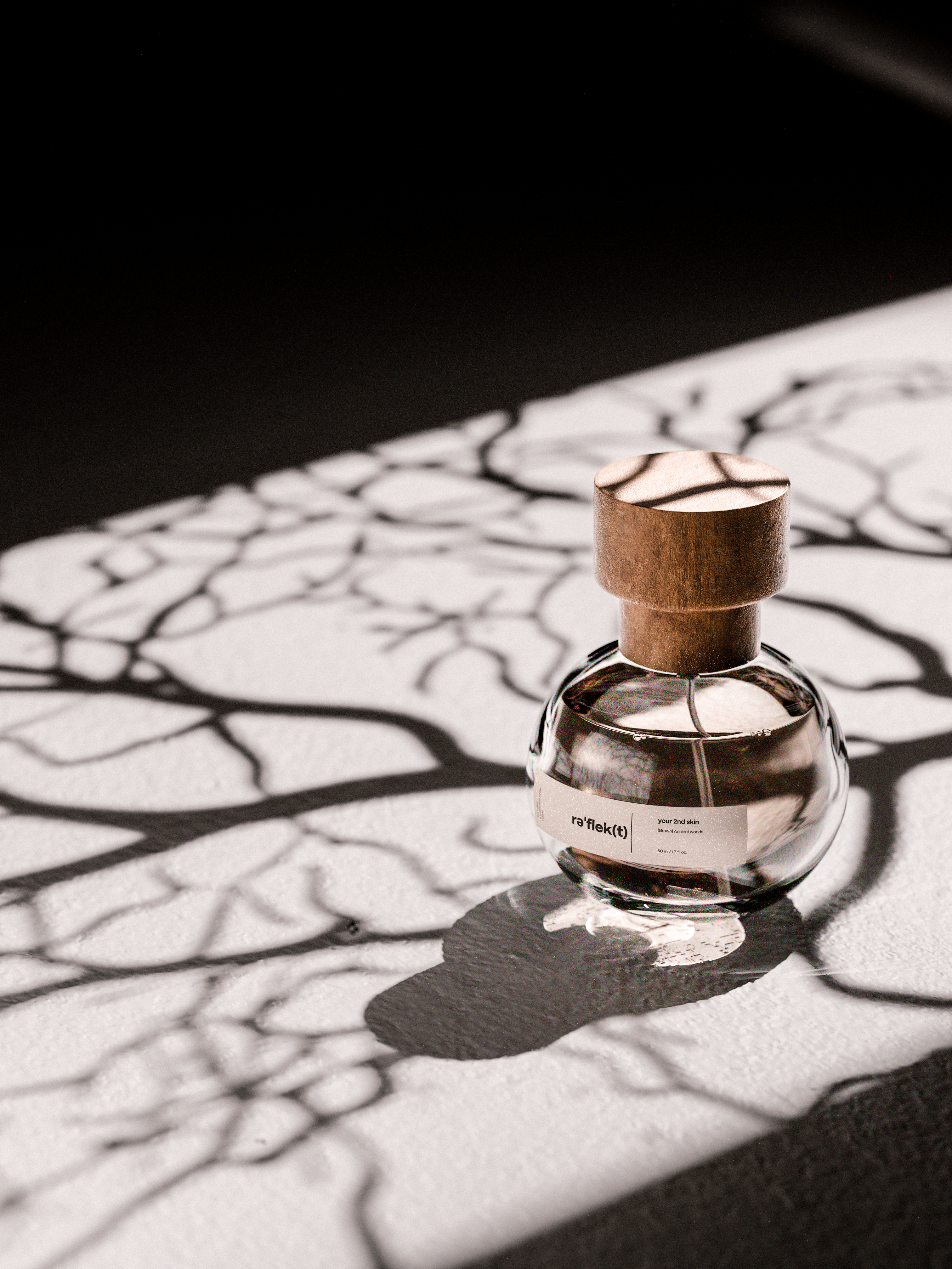3D product render of a glass perfume bottle with a wooden cap on a textured surface with artistic branching shadows